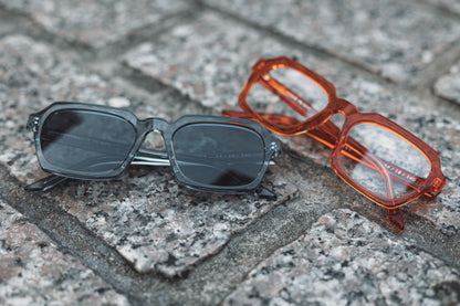 Gafas de sol y espejuelos acetato japonés grises y anaranjadas transparente sobre adoquines