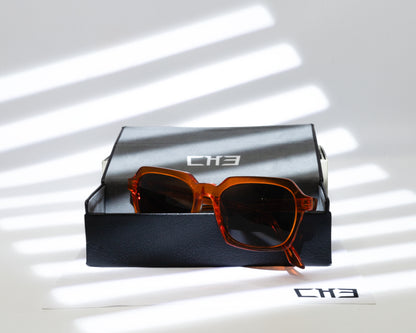 Gafas de sol acetato japonés anaranjadas transparente sobre mesa con sombras.