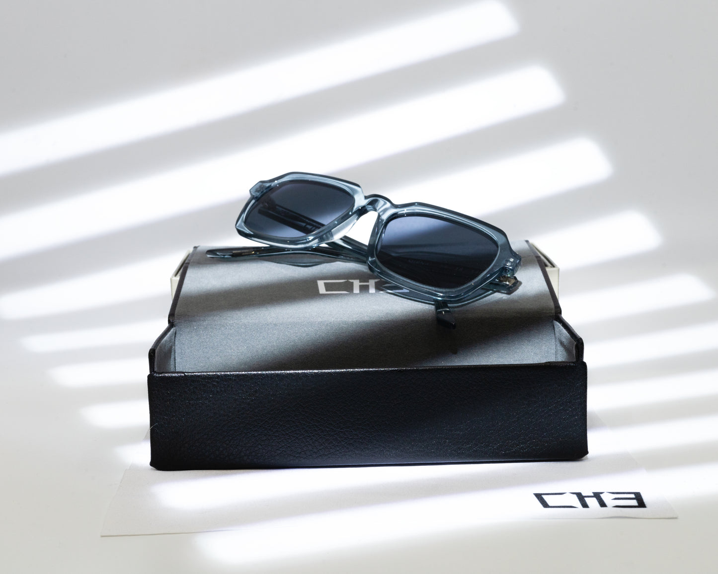 Gafas de sol acetato japonés Smoke Gray transparentes sobre mesa con sombras