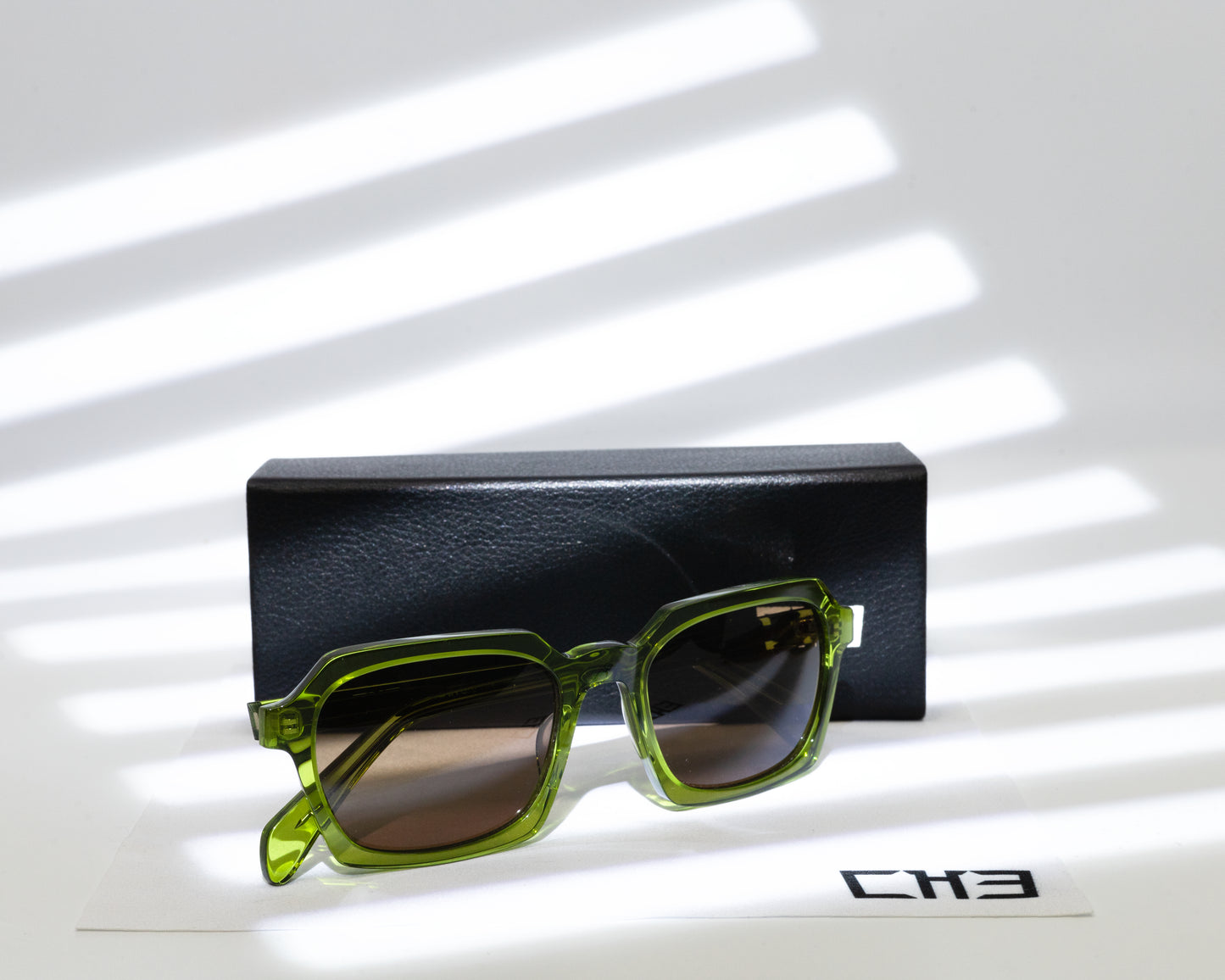 Espejuelo Gafas de sol acetato japonés verde oliva transparente sobre mesa con sombras