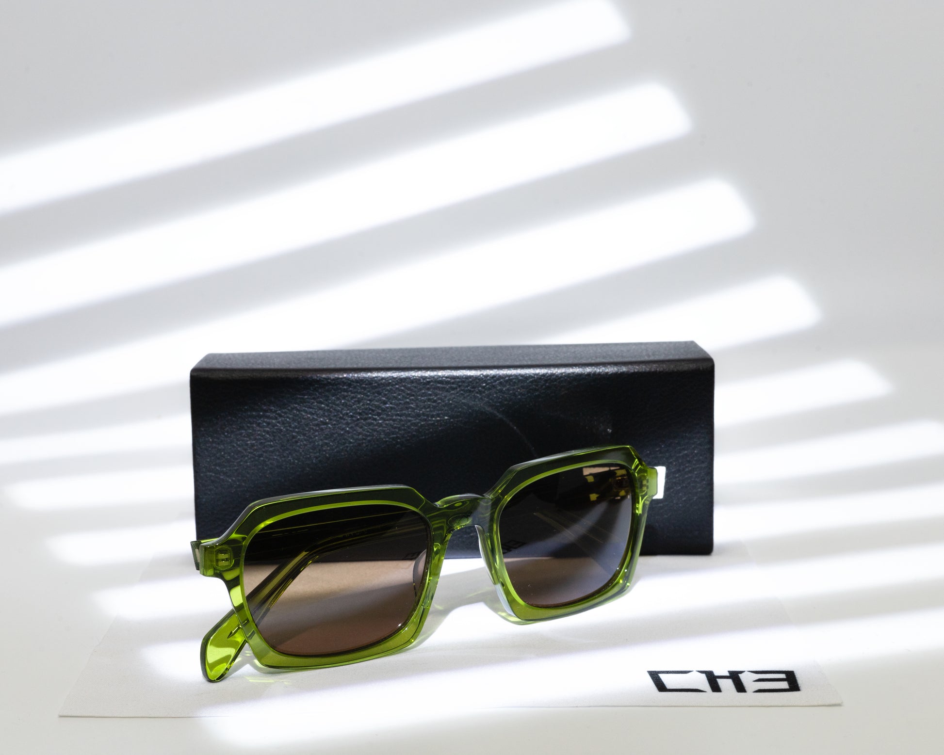 Espejuelo Gafas de sol acetato japonés verde oliva transparente sobre mesa con sombras